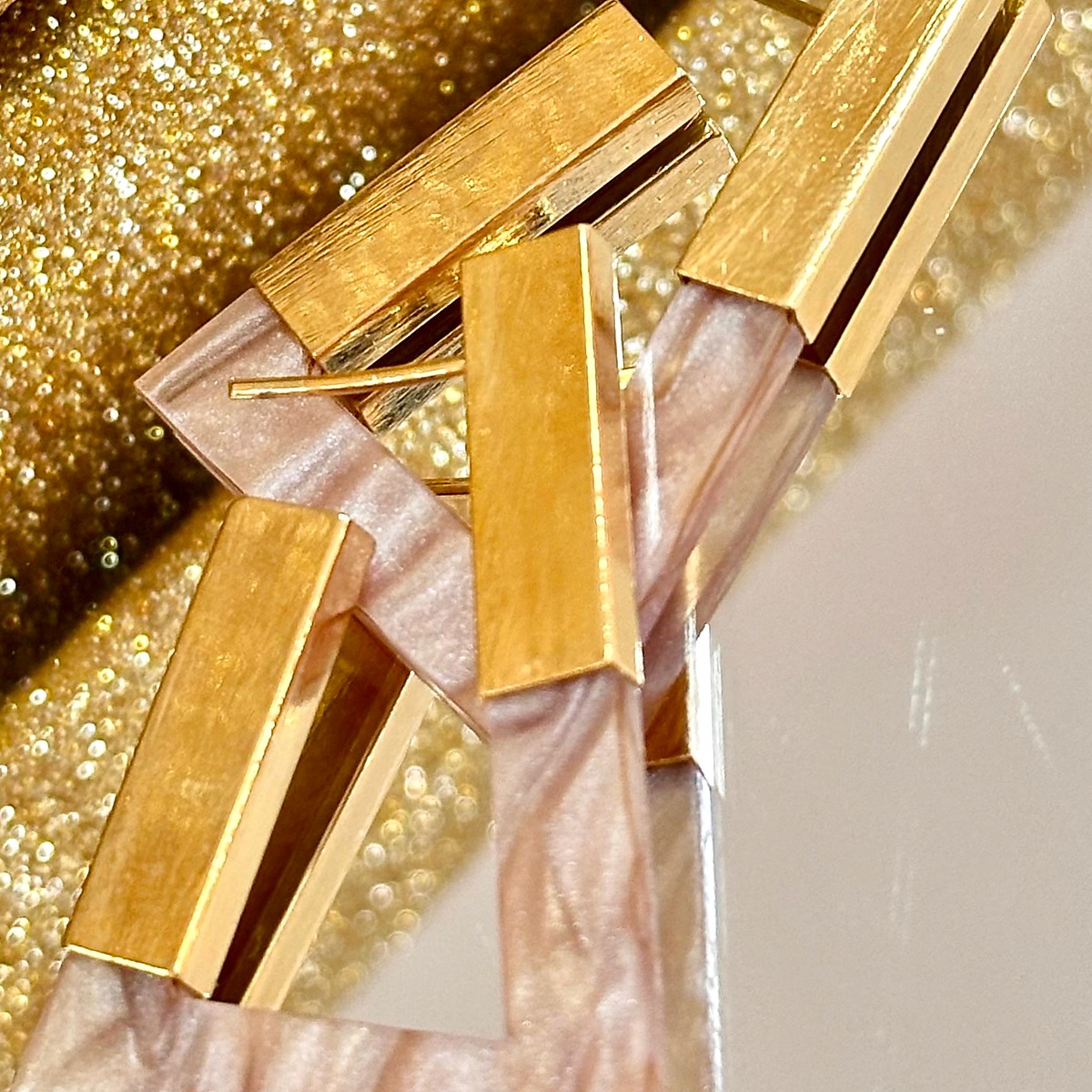 Brinco geométrico dourado com detalhes em resina rosé