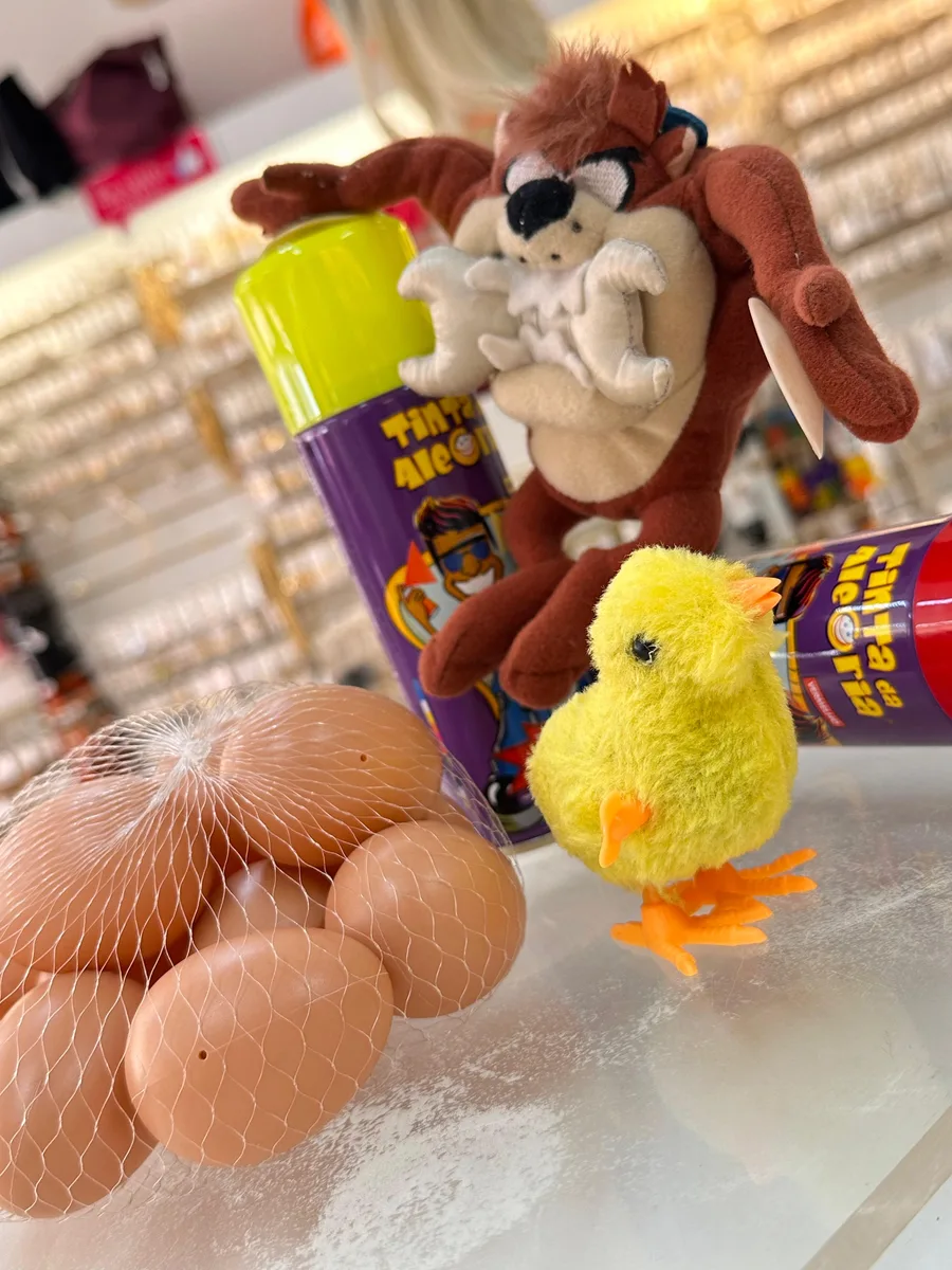 Pintinho amarelo de pelúcia com pezinhos laranja ao lado dos ovinhos de brinquedo, foto 2