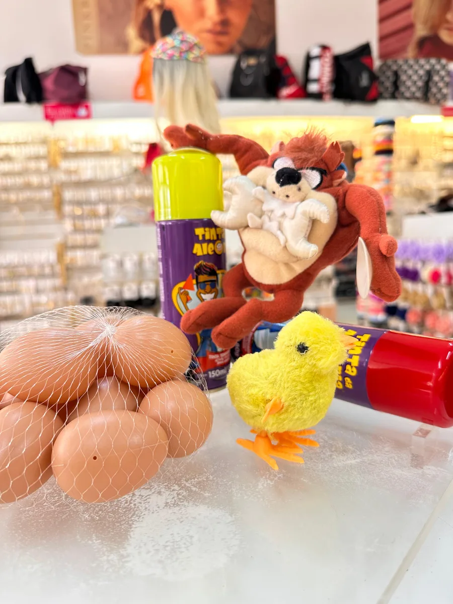 Pintinho amarelo de pelúcia e ovinhos de brinquedo na redinha, foto 1