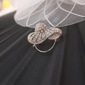 Broche prateado em formato de chapéu cravejado de strass