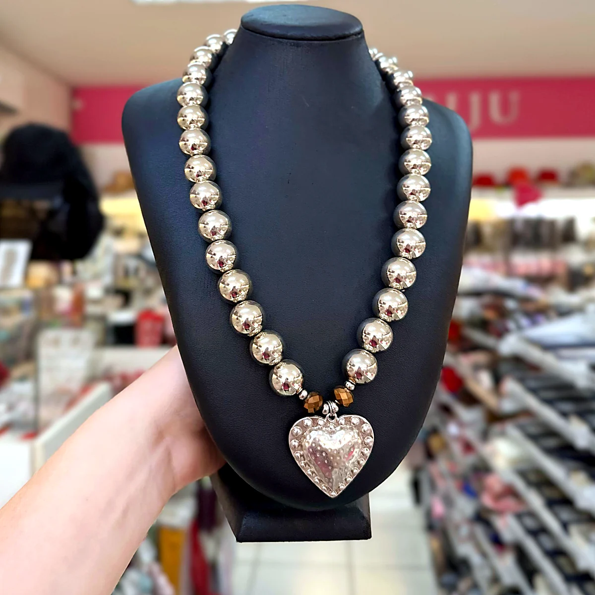 Colar longo de bolas prateadas com pingente de coração martelado em busto preto na loja PinkBiju