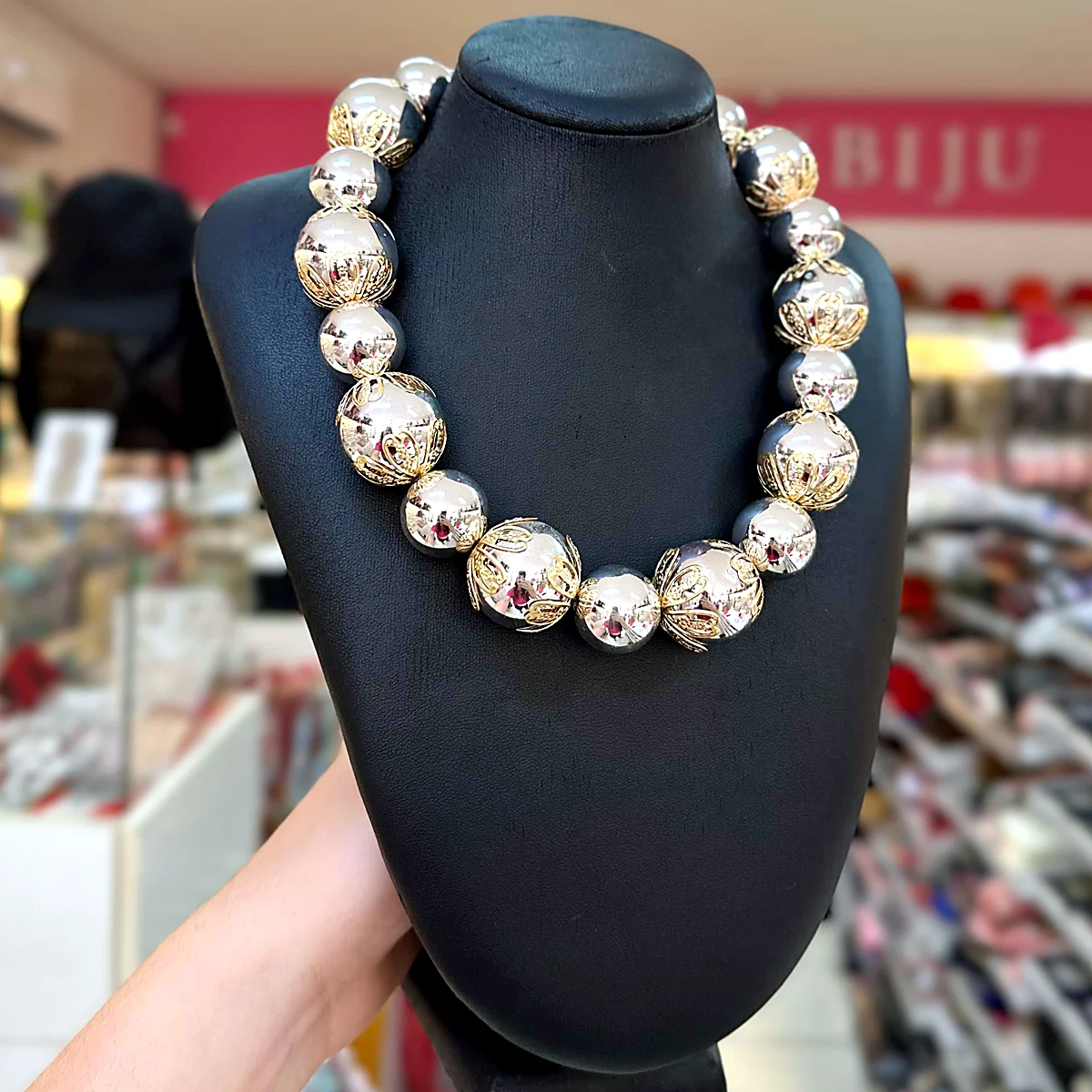 Colar curto de bolas grandes prateadas com detalhes dourados rendados em busto preto na loja PinkBiju